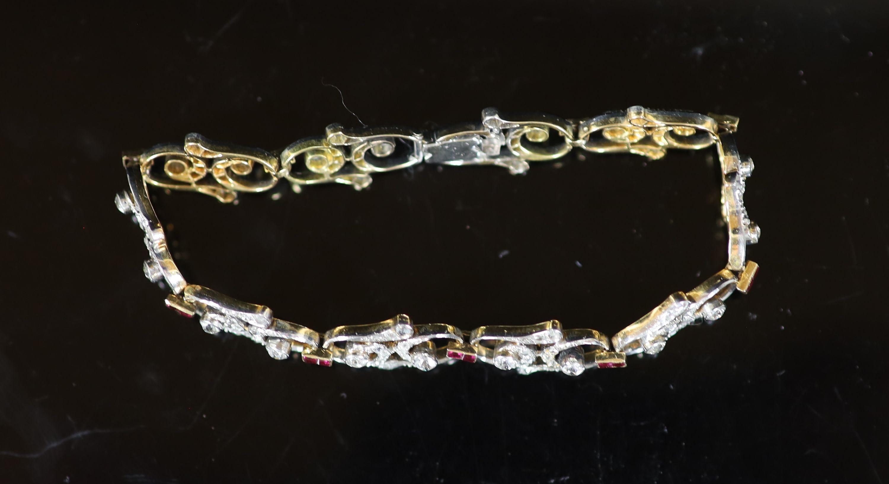 A 1940's/1950's gold and platinum, ruby and diamond set open work scroll link bracelet